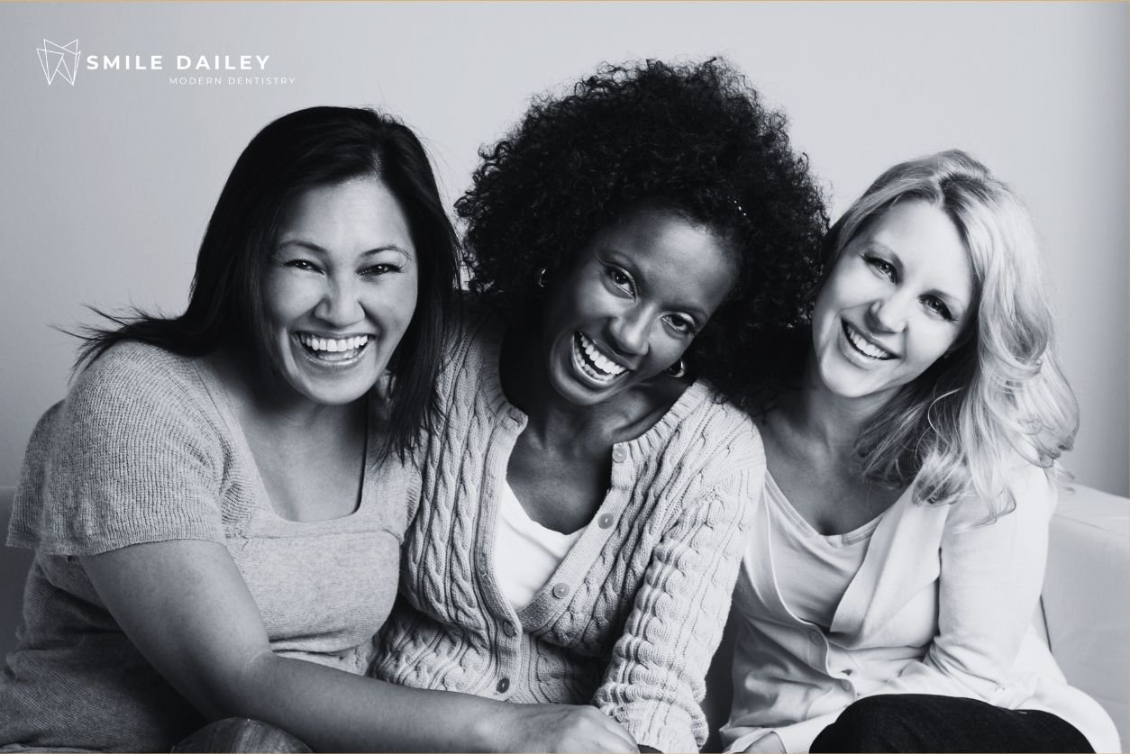 A black and white picture of three women smiling because they are managing bad breath with hygiene.